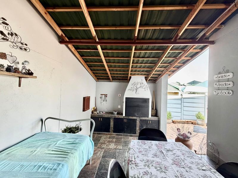 Covered outdoor patio featuring a built-in braai, tiled flooring, and a timber-framed roof, providing a functional space for outdoor entertaining.