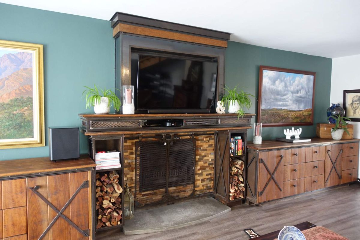 A cozy living room featuring a prominent built-in fireplace with stone detailing, integrated shelving, and wood-look laminate flooring.