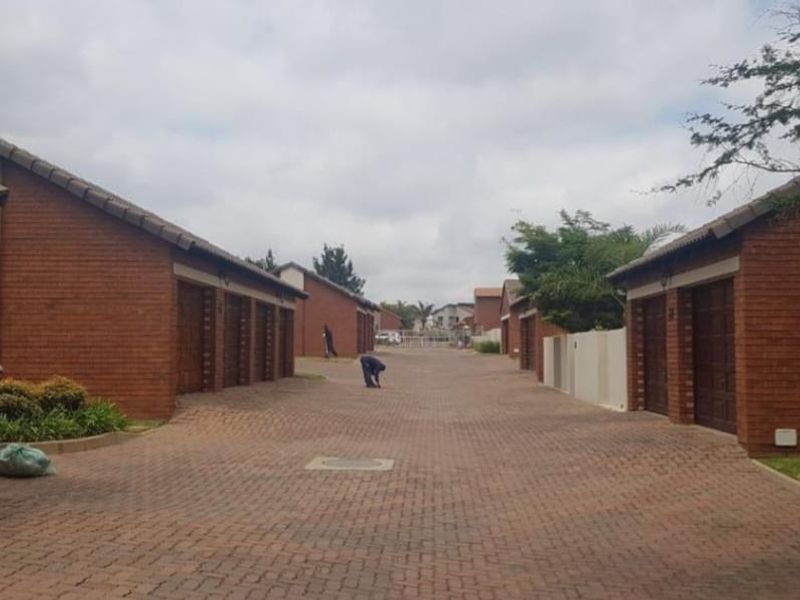 A view of the complex driveway featuring multiple garage units with face-brick exteriors and paved access.