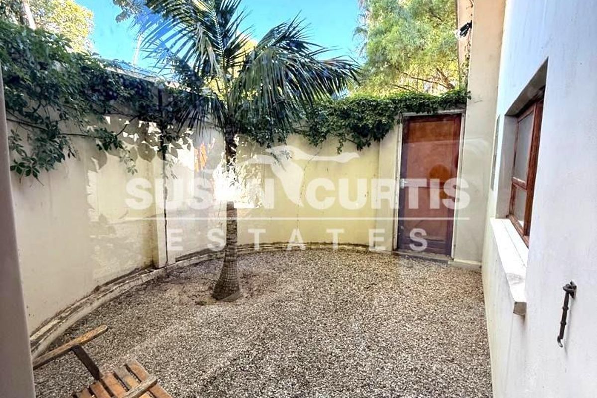 A private rear courtyard featuring a gravel surface, perimeter wall, and direct access to the property.