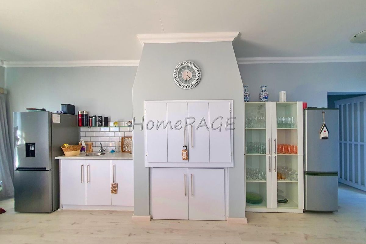 A functional kitchen area featuring white cabinetry, a central built-in storage unit, subway tile backsplash, and integrated sink.