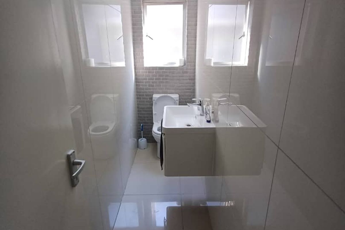 A modern, compact bathroom featuring a wall-mounted vanity, ceramic basin, and tiled finishes throughout, providing a clean and functional space.