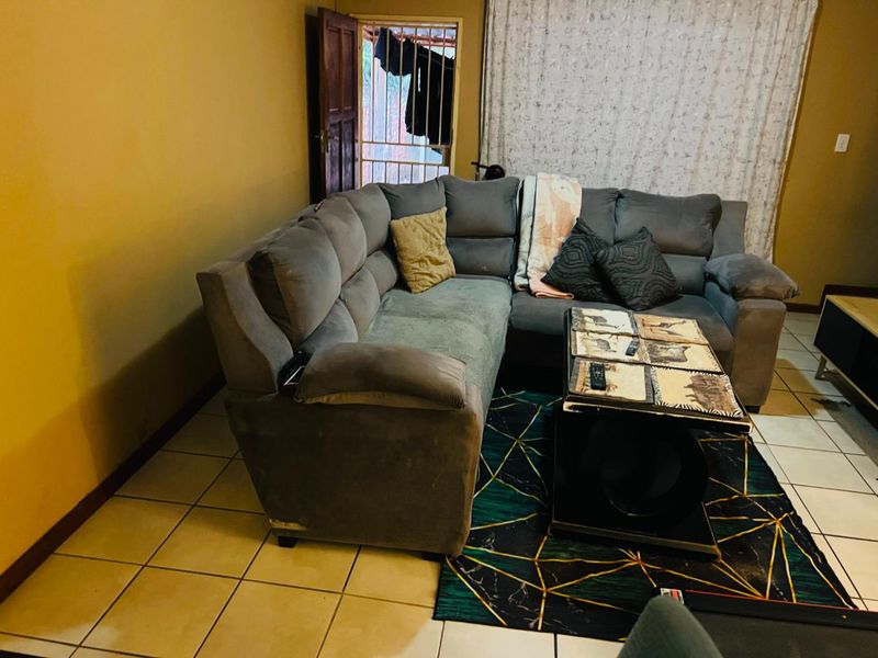 A living room area featuring tiled flooring and access to an exterior security gate, requiring cosmetic updates to improve the overall aesthetic.