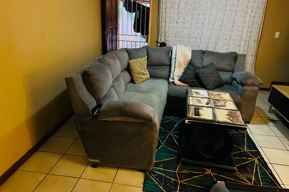 A living room area featuring tiled flooring and access to an exterior security gate, requiring cosmetic updates to improve the overall aesthetic.