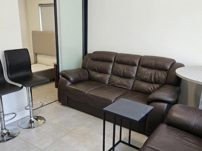 Open plan living area featuring tiled flooring and a modern sliding glass partition leading to an adjacent bedroom space.