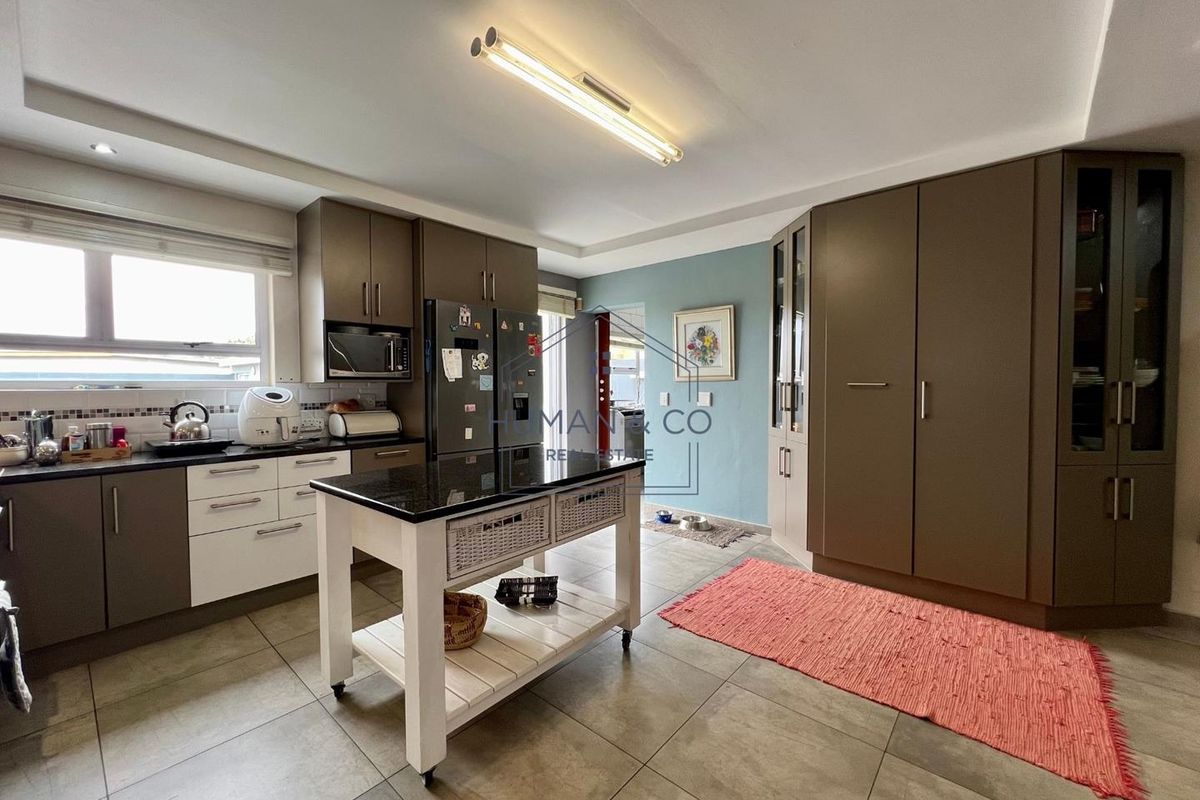 A modern kitchen featuring two-tone cabinetry, dark stone countertops, tiled flooring, and ample built-in storage space.