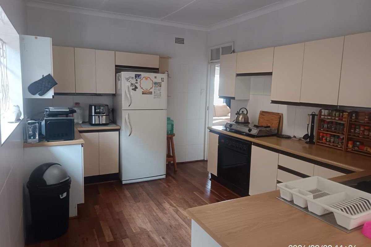 A functional kitchen featuring light-toned cabinetry, laminate countertops, a built-in oven with gas hob, and timber flooring.