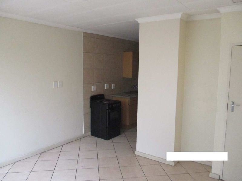 A compact, empty kitchen area featuring tiled flooring, built-in cabinetry, and a freestanding stove, requiring cosmetic updates to improve its appeal.