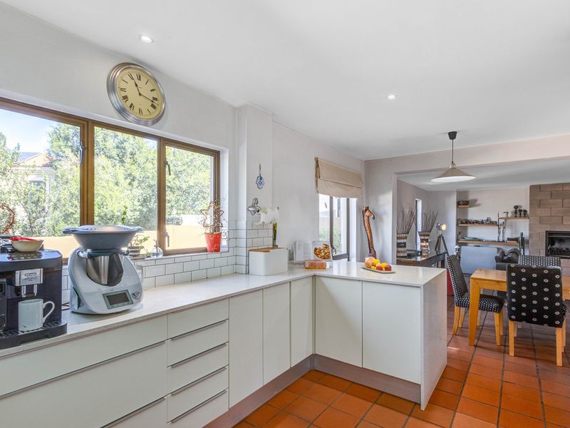 Open-plan kitchen and living area featuring terracotta flooring, subway tile backsplash, and a built-in fireplace, creating a functional and connected living space.