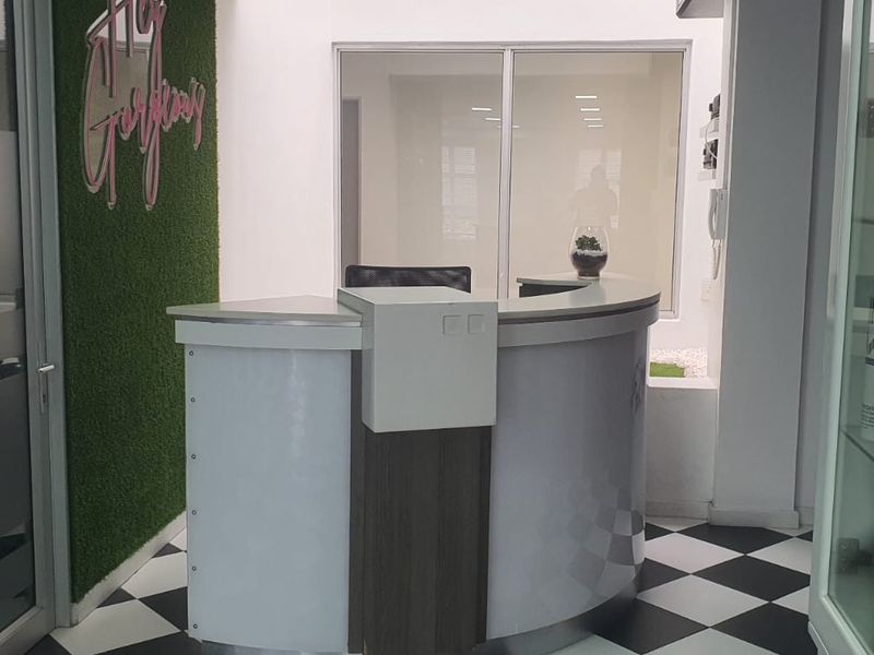 A modern reception area featuring a curved desk, checkered flooring, and glass partitions, creating a professional and welcoming entrance space.