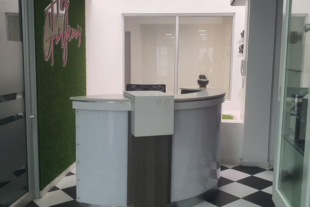 A modern reception area featuring a curved desk, checkered flooring, and glass partitions, creating a professional and welcoming entrance space.