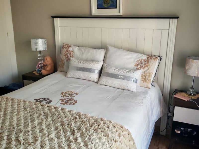 A cozy bedroom featuring laminate flooring and a built-in headboard, creating a comfortable and functional sleeping space.