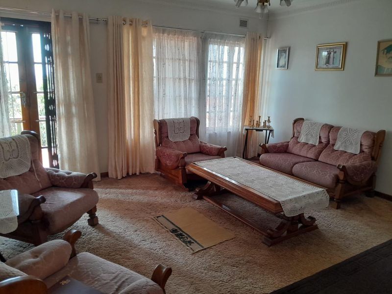 A traditional living room featuring carpet flooring, decorative cornice, and access to an outdoor area through classic french doors.