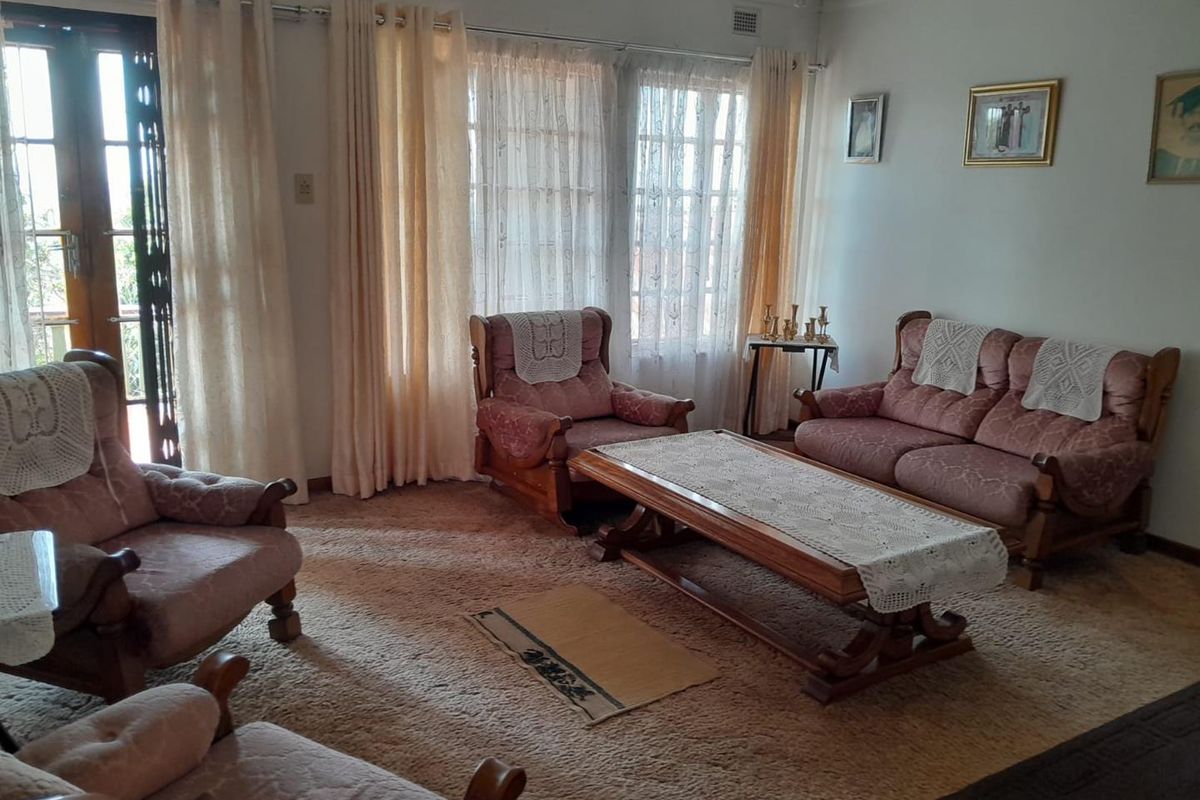 A traditional living room featuring carpet flooring, decorative cornice, and access to an outdoor area through classic french doors.