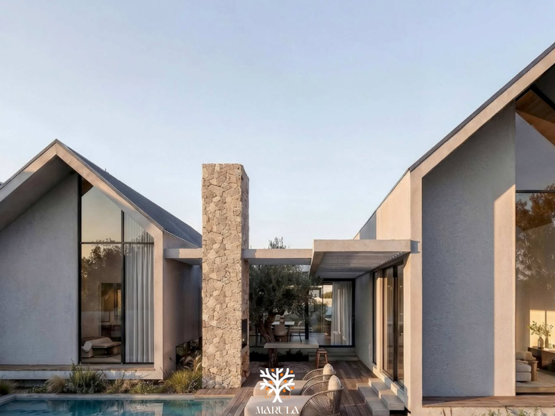 Modern architectural townhouse exterior featuring a swimming pool, stone chimney, timber decking, and expansive floor-to-ceiling windows connecting indoor and outdoor living spaces.