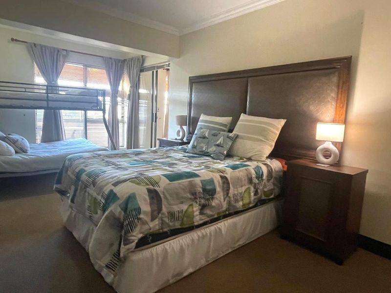 Spacious bedroom featuring crown molding, neutral wall finishes, and access to a private balcony through sliding glass doors.