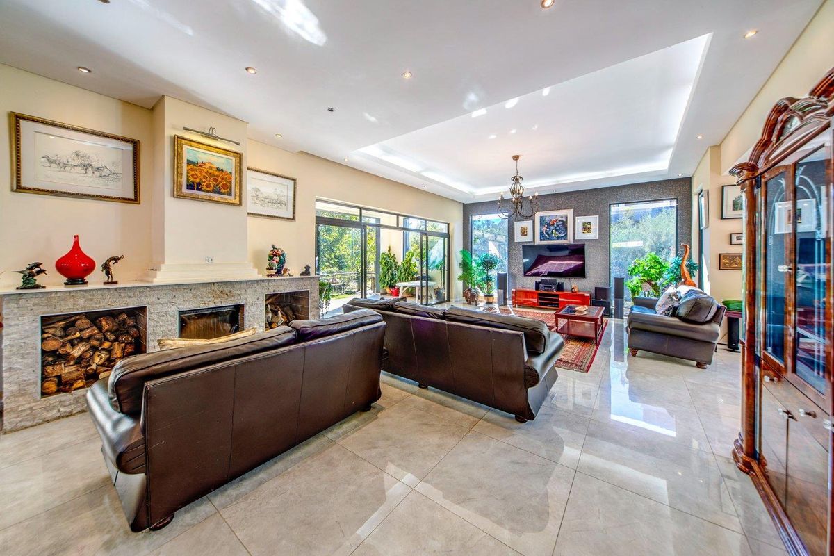Spacious living room featuring large format floor tiles, a stone-clad fireplace, recessed ceiling lighting, and expansive glass sliding doors leading to the outdoor area.