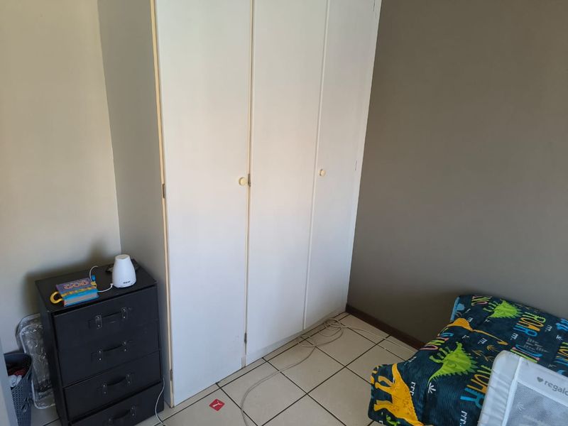 A bedroom featuring a white built-in wardrobe and tiled flooring, providing functional storage space within the room.