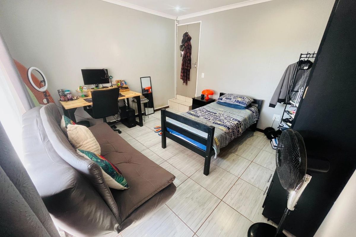 A functional bedroom featuring tiled flooring and a neutral wall finish, suitable for use as a sleeping area or home office space.