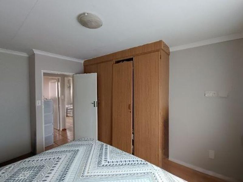 Bedroom featuring a built-in wooden wardrobe and neutral wall finishes, providing functional storage space within the apartment.