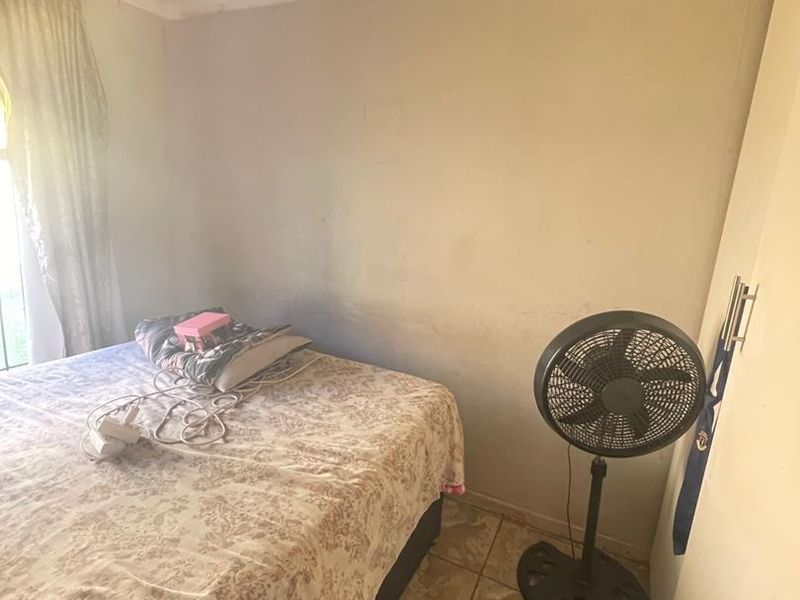 A bedroom featuring tiled flooring and a built-in cupboard, showing signs of ceiling water damage and wall wear.