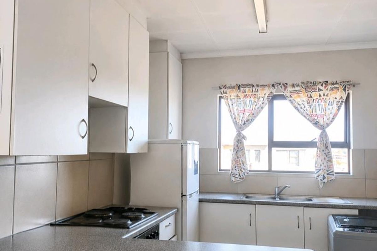 Functional kitchen featuring white cabinetry, laminate countertops, a built-in hob, and a double sink with a window view.