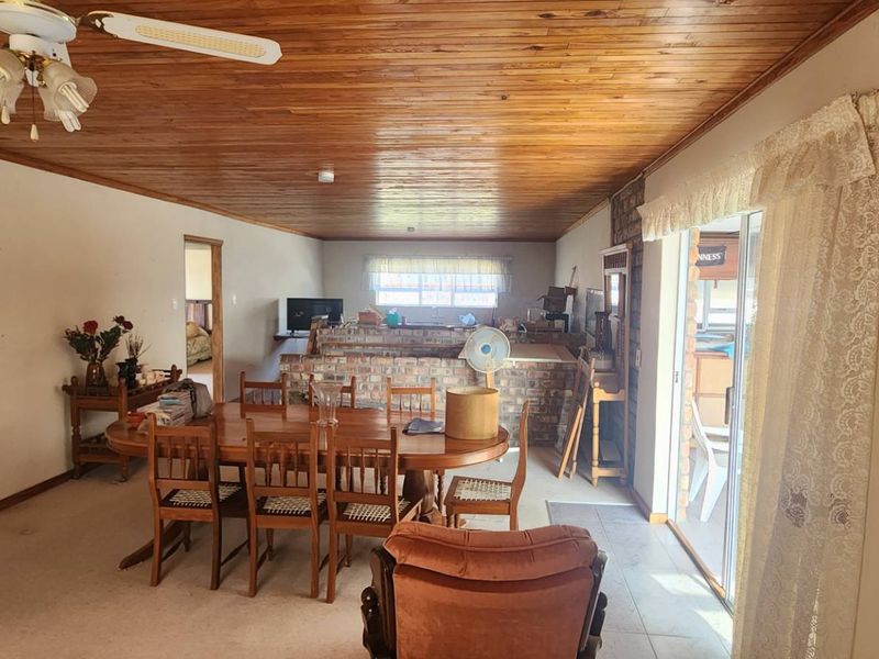 Open plan living and dining area featuring a timber ceiling, exposed brick wall, and sliding door access to the exterior.