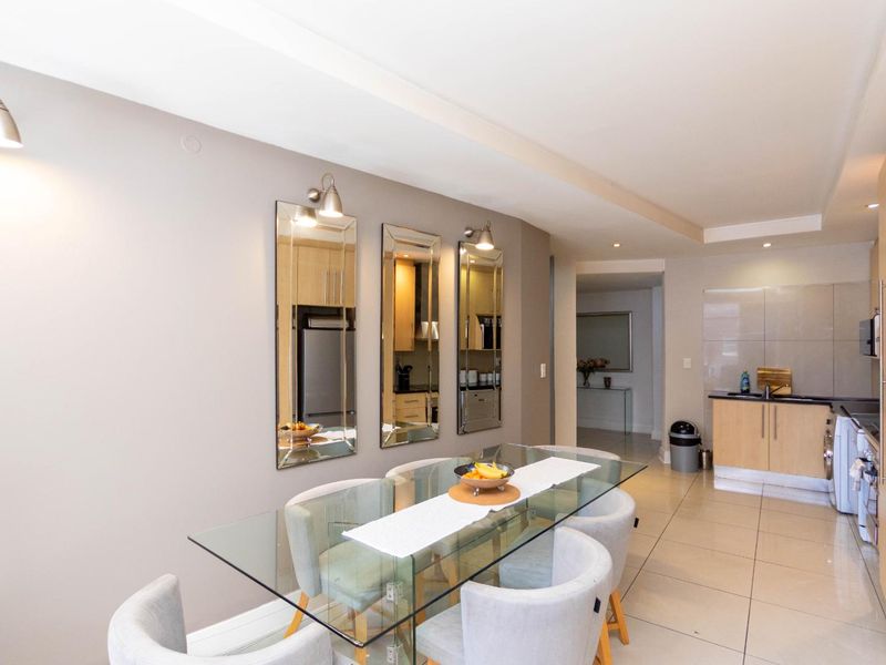 Open-plan living and dining area featuring tiled flooring, modern kitchen cabinetry, and integrated lighting, creating a functional and cohesive space.