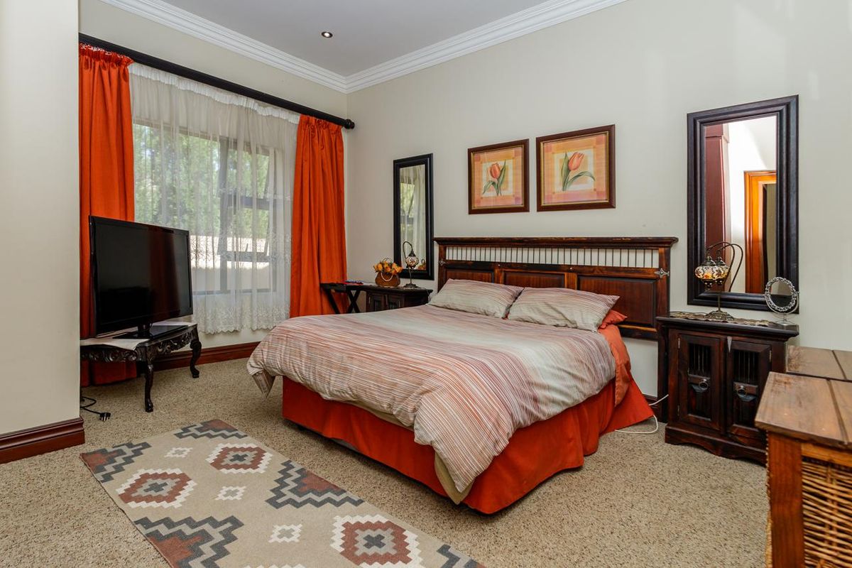A well-maintained bedroom featuring neutral walls, crown molding, carpeted flooring, and a large window with integrated curtain rods.