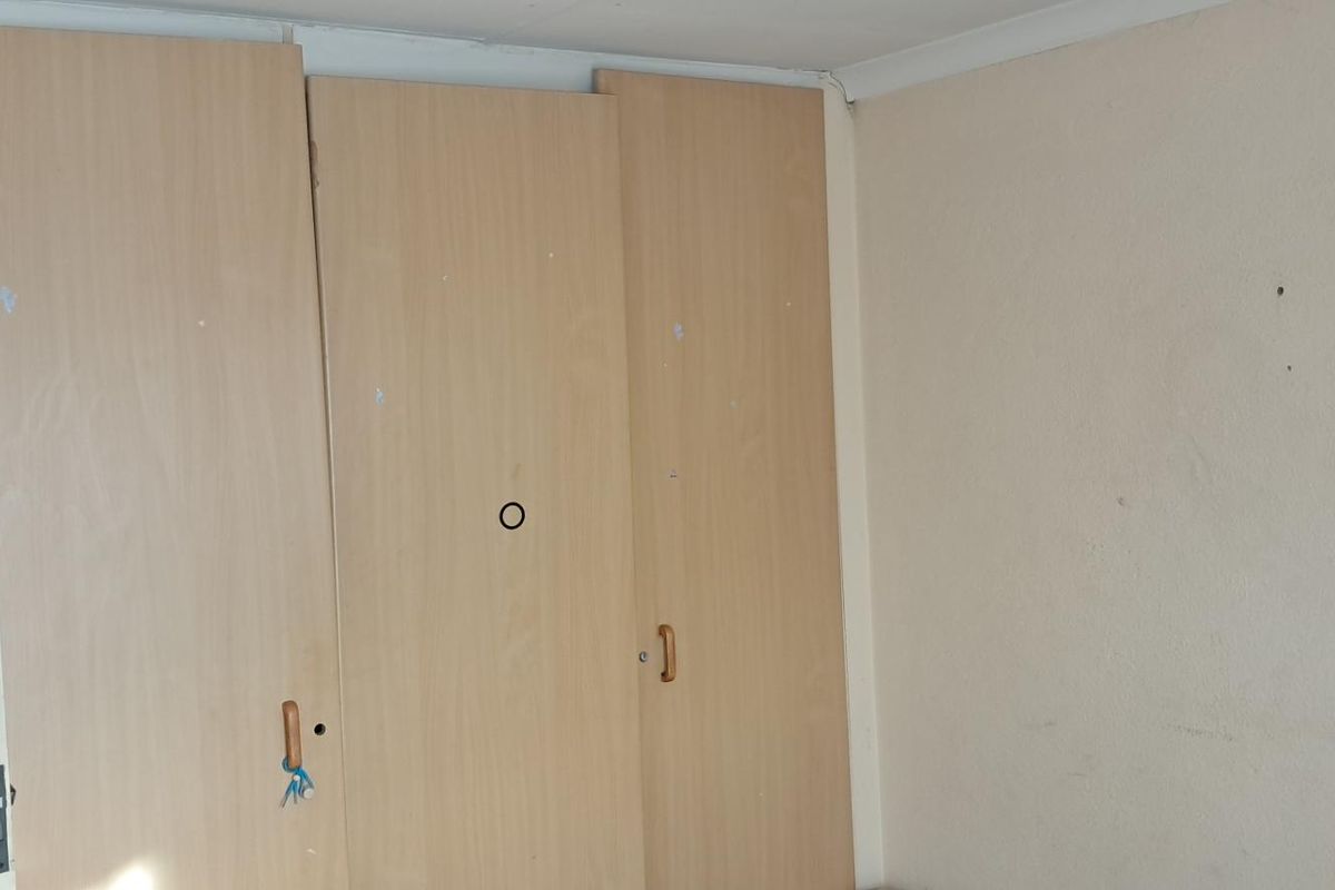 A bedroom featuring built-in wooden cabinetry with visible wear and scuffed wall surfaces.