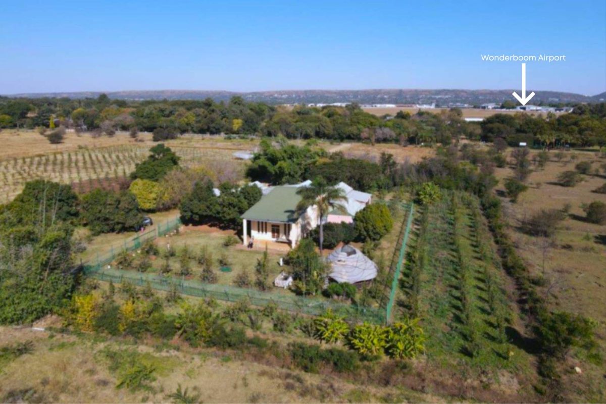 Aerial view of the farm property featuring a main dwelling, established garden, and surrounding agricultural land with proximity to Wonderboom Airport.
