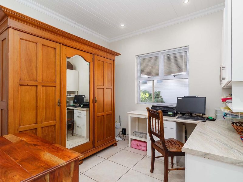 A functional home office featuring tiled flooring, built-in desk space, recessed lighting, and crown molding, providing a practical workspace.