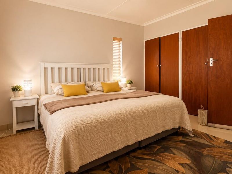 A well-maintained bedroom featuring neutral walls, tiled flooring, and ample storage with built-in wooden cupboards.
