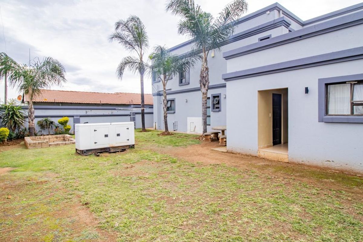 Rear view of the property featuring a private garden, paved area, and exterior access to the main building structure.