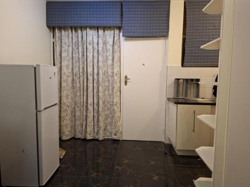 A compact kitchen area featuring tiled flooring, built-in cabinetry, and a sink, providing a functional space for meal preparation.