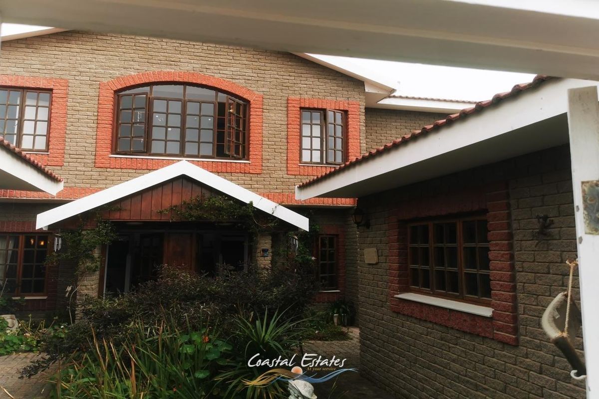 A view of the property's exterior courtyard featuring brick facade detailing, timber-framed windows, and a landscaped garden area.