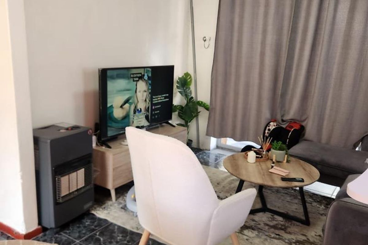 A living room area featuring dark tiled flooring and visible ceiling water damage, requiring maintenance to restore the space.