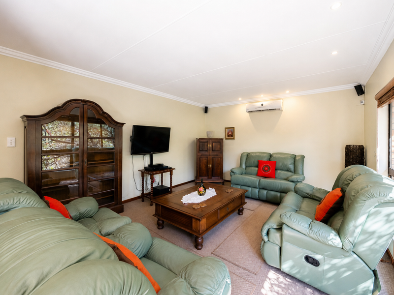 A comfortable living room featuring neutral walls, recessed downlighting, a split-system air conditioner, and large windows allowing for natural light.