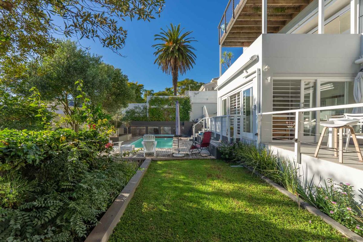 A well-maintained rear garden featuring a swimming pool, timber decking, and a multi-level outdoor entertainment area with direct access to the house.