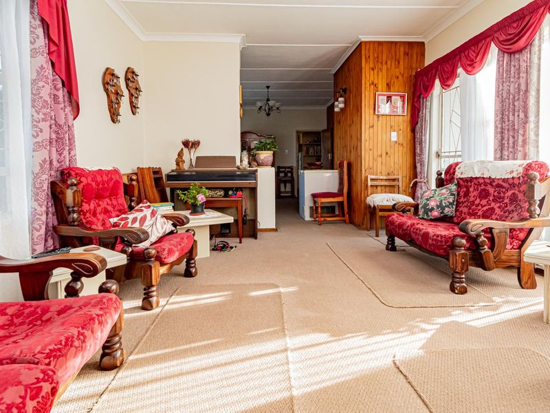 A spacious living area featuring timber wall paneling, neutral carpeting, and natural light, offering a traditional layout with potential for modern updates.