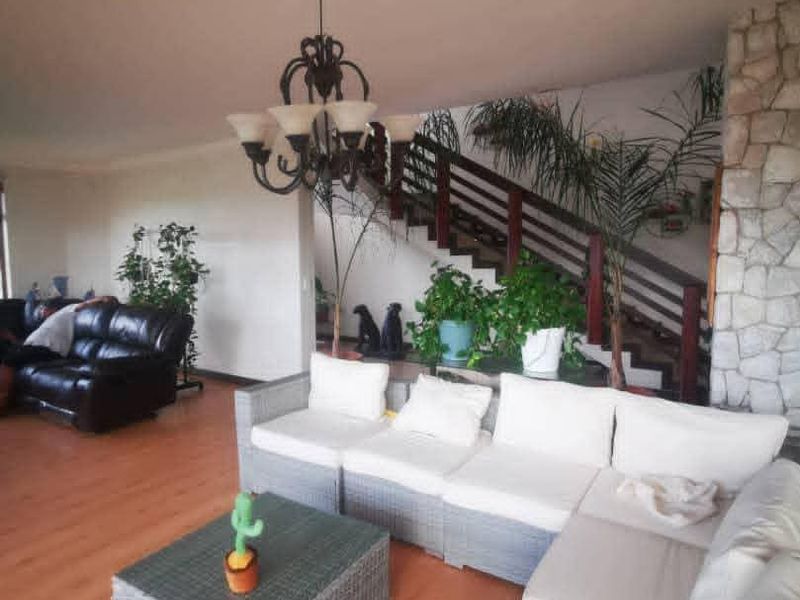 Spacious living area featuring a stone fireplace, timber staircase with balustrade, and laminate flooring, offering a warm and inviting atmosphere.