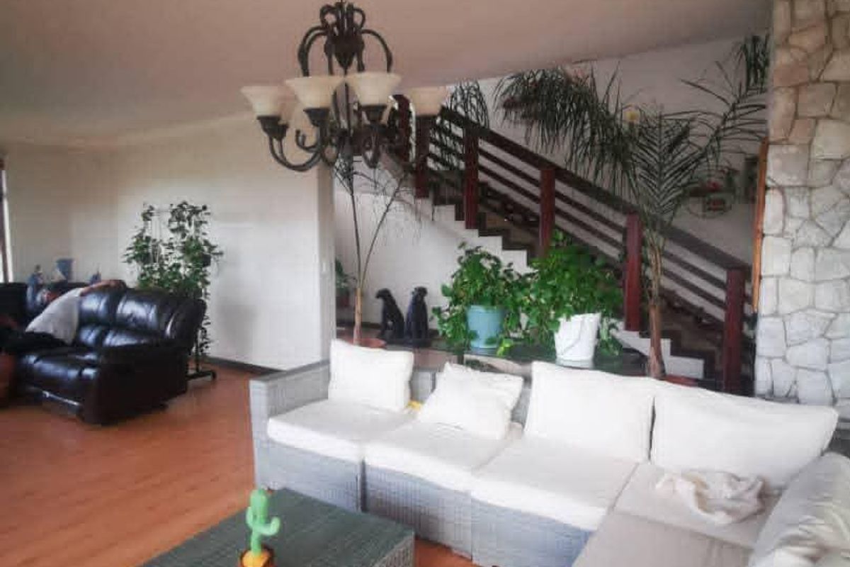 Spacious living area featuring a stone fireplace, timber staircase with balustrade, and laminate flooring, offering a warm and inviting atmosphere.