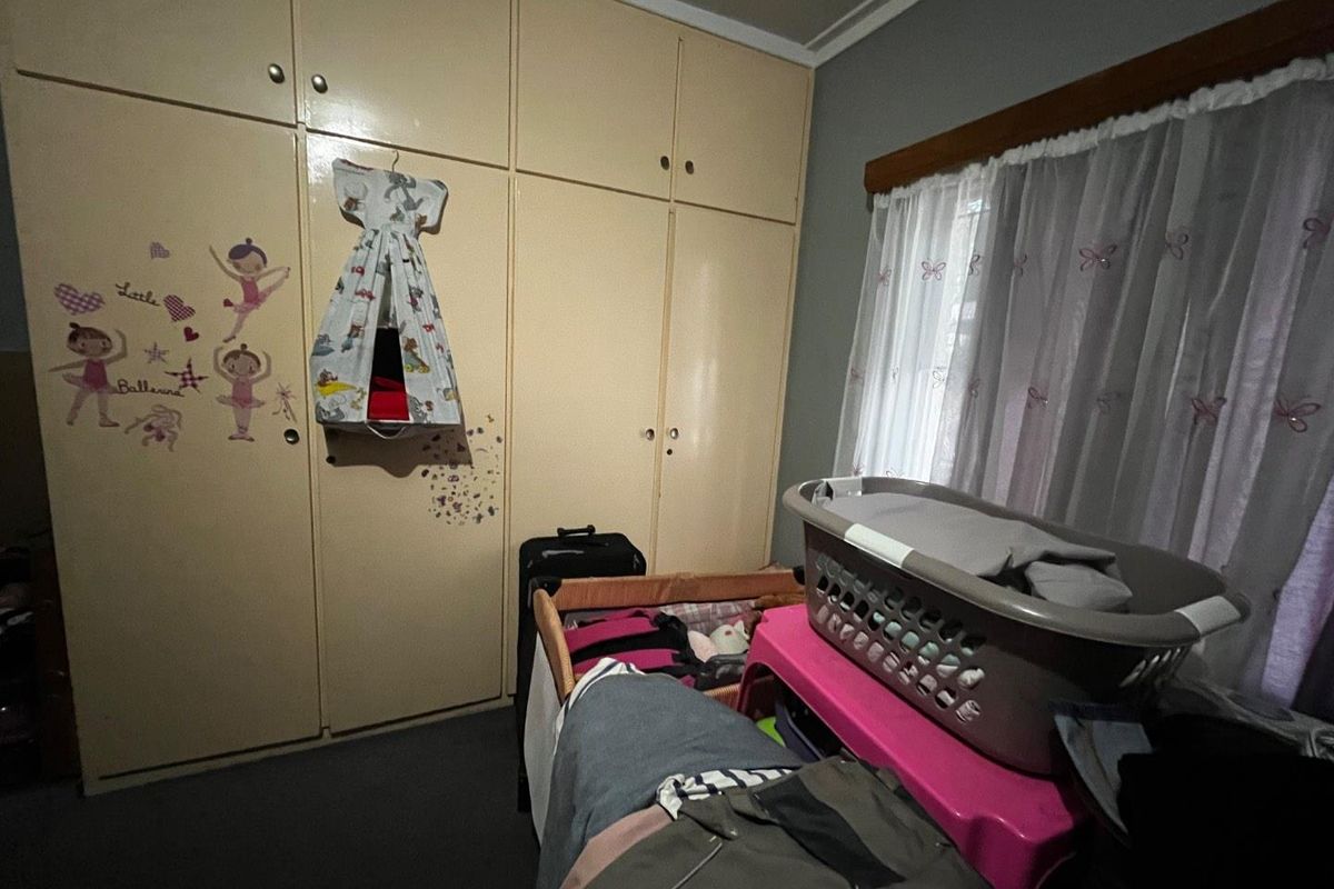 A bedroom featuring floor-to-ceiling built-in cupboards and a window with curtains.