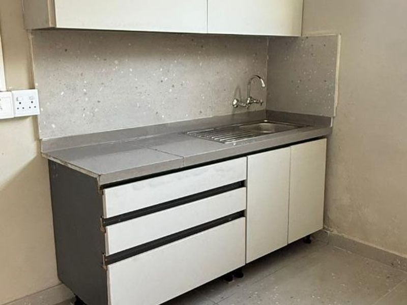 A compact scullery area featuring built-in cabinetry, a stainless steel sink, and tiled finishes, providing a functional utility space.