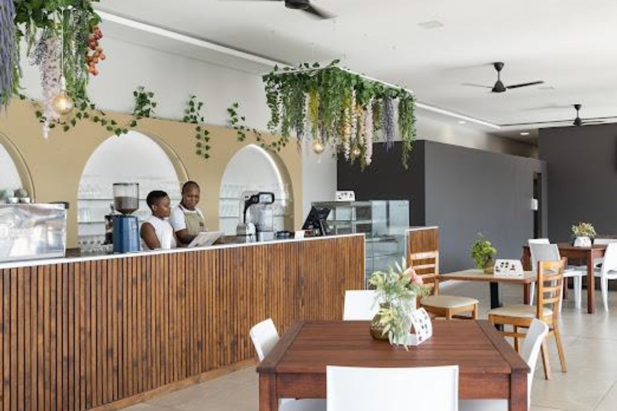 Modern open-plan commercial space featuring a slatted timber service counter, decorative arched wall niches, and contemporary ceiling fans.
