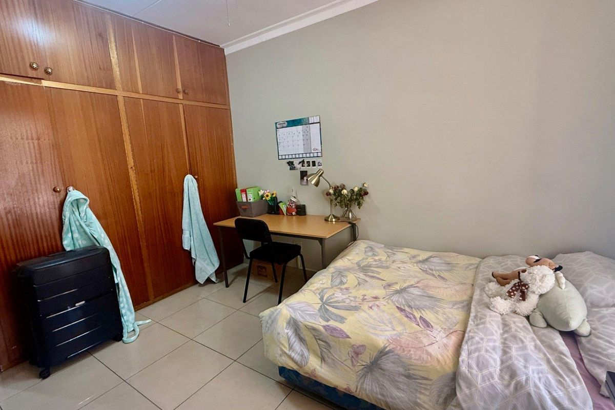A functional bedroom featuring built-in wooden cabinetry and tiled flooring, providing ample storage and a practical layout.