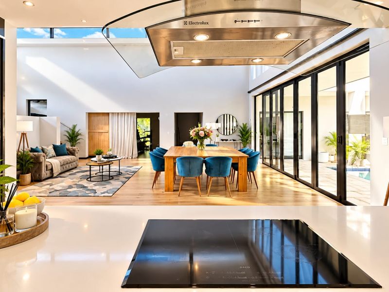 Spacious open-plan living and dining area featuring a modern kitchen with a large island, induction cooktop, and seamless flow to the outdoor patio.