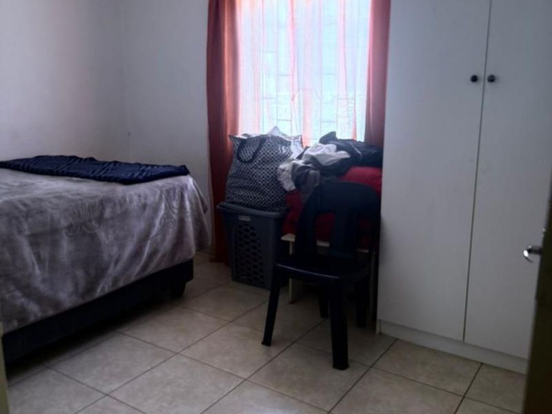 A functional bedroom featuring tiled flooring and a built-in wardrobe, providing essential storage space.