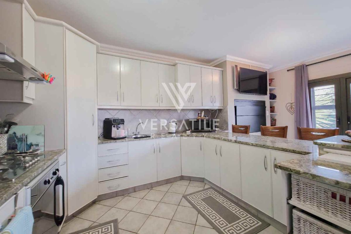 A functional kitchen featuring ample built-in cabinetry, granite countertops, a gas hob with extractor fan, and a breakfast nook area with tiled flooring.