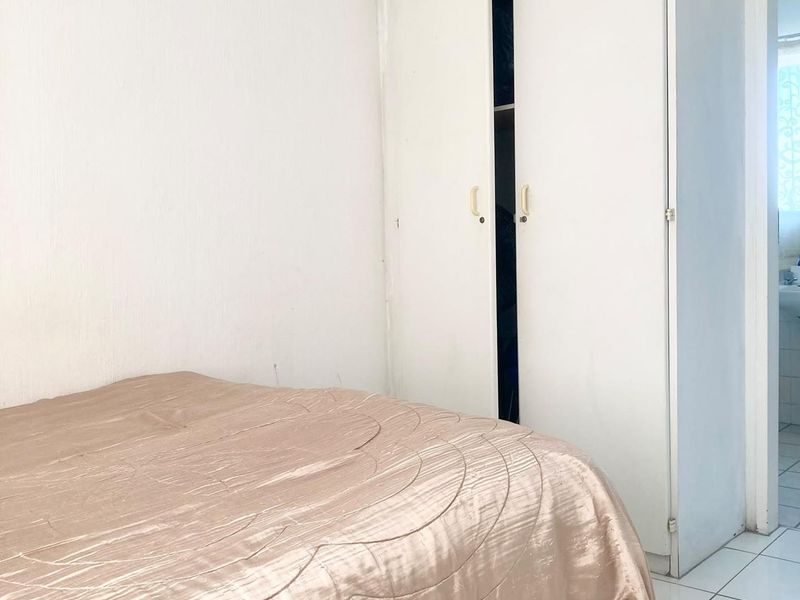 A bedroom featuring white walls, tiled flooring, and a built-in wardrobe with double doors.